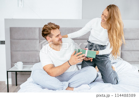 Pretty cheerful fair-haired woman congratulating her boyfriend with gift 114488389