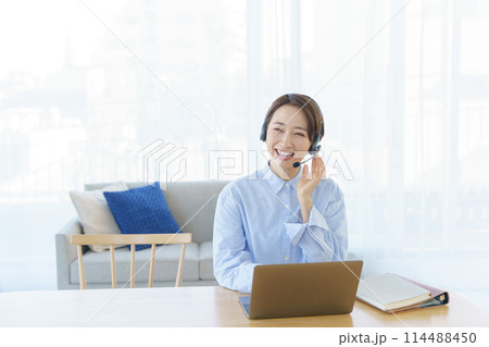 ヘッドマイクをつけてパソコンを操作する女性 114488450