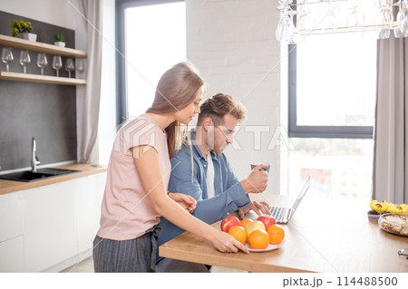 young couple watching video from the laptom in the kitchen with modern interior 114488500