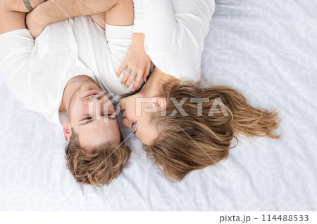 awesome girl is kissing a handsome guy while resting on the bed 114488533
