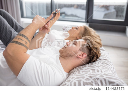 Young couple with smartphones in their bed Young couple with smartphones in their bed 114488573