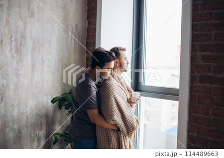 two handsome homosexual guys while standing near window 114489663