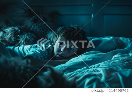 scared little boy in bed with open eyes because child afraid of the dark at night 114490762