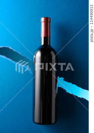 Bottle of red wine on a dark blue background. 114490913