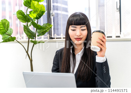 コーヒーを飲みながら仕事をする女性社員 114491571