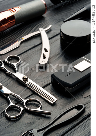 Professional Barber Tools Laid Out on Dark Wooden Surface 114492312