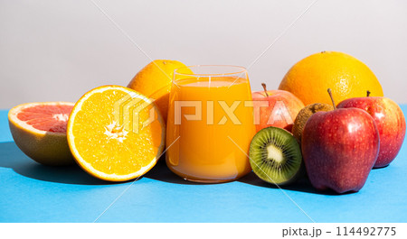 Multifruit juice in a glass among fresh fruits on blue and white background Multifruit juice in a glass among fresh fruits on blue and white background 114492775