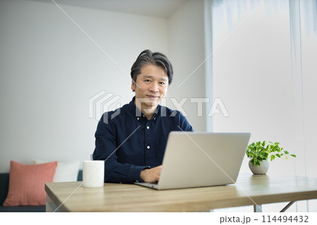 リビングでテレワークをするミドル男性 リビングでテレワークをするミドル男性 114494432
