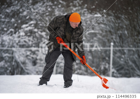 Man shoveling snow with orange shovel	 114496335