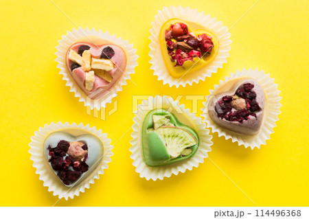 chocolate sweets in the form of a heart with fruits and nuts on a colored background. top view with space for text, holiday concept 114496368