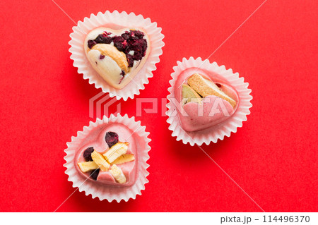 chocolate sweets in the form of a heart with fruits and nuts on a colored background. top view with space for text, holiday concept 114496370