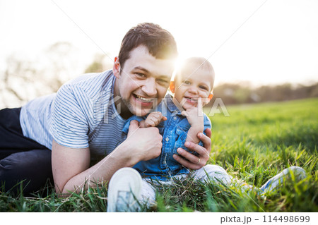Father playing with little toddler boy in grass, having fun during warm spring day. Father's day concept. Father playing with little toddler boy in grass, having fun during warm spring day. Father's day concept. 114498699