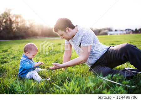 Father playing with little toddler boy in grass, having fun during warm spring day. Father's day concept. Father playing with little toddler boy in grass, having fun during warm spring day. Father's day concept. 114498706