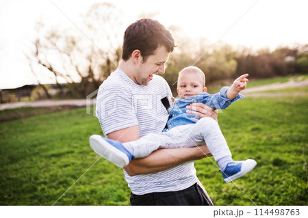 Father holding little toddler boy playing, having fun during warm spring day. Father's day concept. Father holding little toddler boy playing, having fun during warm spring day. Father's day concept. 114498763