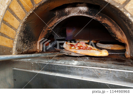Pizza Cooking in Brick Oven 114498968