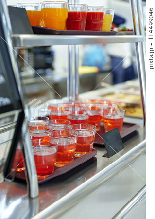 Colorful Array of Fruit Juice Cups on a Serving Cart in a Cafeteria 114499046