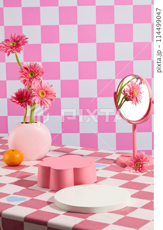 An empty flower shaped pedestal and round white podium on pink checkered background, decorated by gerbera daisy flower. Photo was taken from front view, copy space for text 114499047