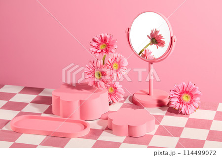 Pink background against various types of blank pedestal, a desk mirror and gerbera daisy flower decorated.  Advertising photo with space for presenting product has natural origin 114499072