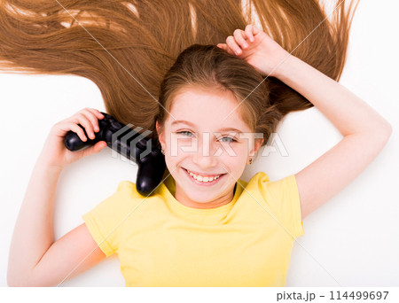 Smiling girl stretching on the floor with joystick in hand, tired after playing computer games 114499697