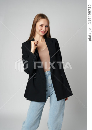 Young woman standing with her arms lifted high above her head expressing joy and triumph 114499730