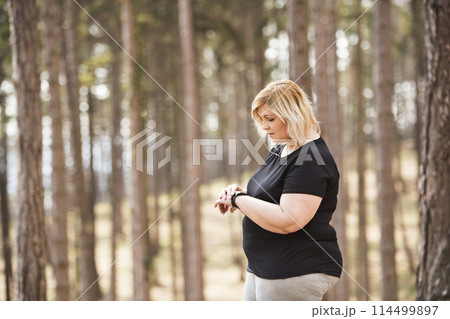 Overweight woman preparing for run in nature. Exercising outdoors for people with obesity. 114499897