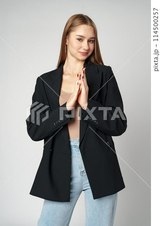 Young Woman Wearing Black Jacket and Jeans posing on gray background studio shot . 114500257
