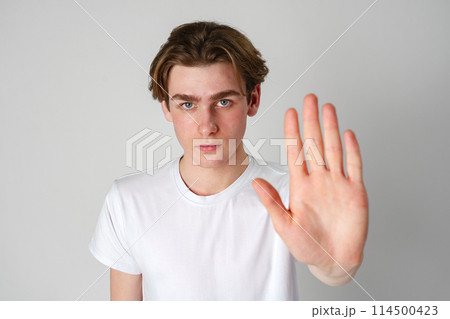 Young Man in White T-Shirt Showing Stop Gesture With Hand Young Man in White T-Shirt Showing Stop Gesture With Hand 114500423