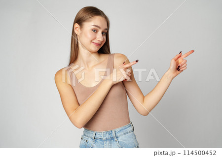 Young Woman in Tank Top Pointing at Something on gray background Young Woman in Tank Top Pointing at Something on gray background 114500452