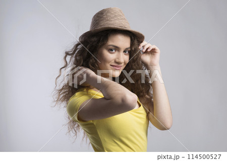 Portrait of a gorgeous teenage girl with curly hair and hat. Studio shot, white background with copy space 114500527