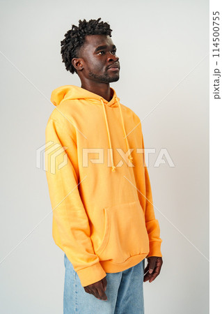 African Man in Yellow Hoodie in Front of Gray Wall 114500755
