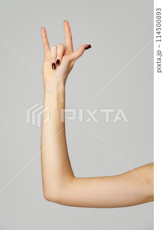 Female hand gesturing rock sign on gray background Female hand gesturing rock sign on gray background 114500893