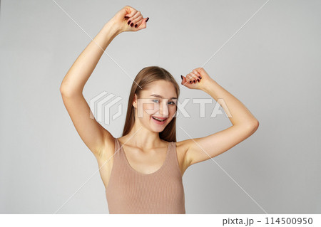 Young woman standing with her arms lifted high above her head expressing joy and triumph Young woman standing with her arms lifted high above her head expressing joy and triumph 114500950