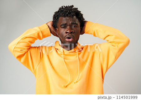 African Man in Yellow Hoodie Holding Head and Smiling African Man in Yellow Hoodie Holding Head and Smiling 114501999