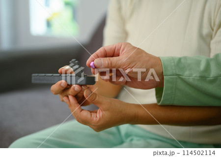 Closeup mature man taking prescription medicine on couch at home. Healthcare and medication concept 114502114
