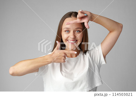 Young woman making frame with fingers on a gray background Young woman making frame with fingers on a gray background 114503021