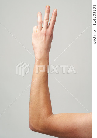 Male hand showing three fingers on gray background Male hand showing three fingers on gray background 114503108