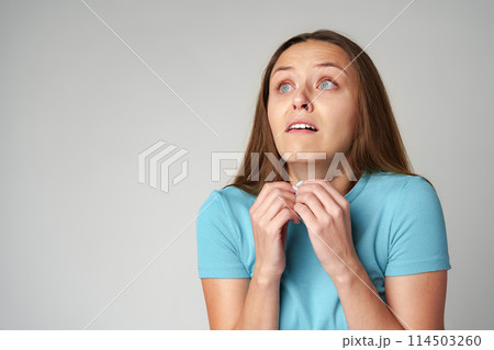 Emotional frightened young woman on gray background Emotional frightened young woman on gray background 114503260