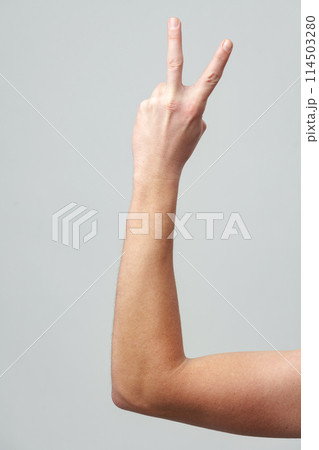 Male hand showing two fingers on gray background 114503280