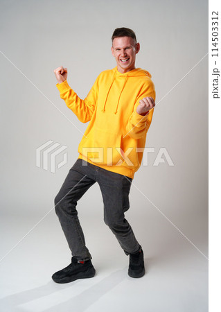 Portrait of a satisfied young man celebrating success over gray background Portrait of a satisfied young man celebrating success over gray background 114503312