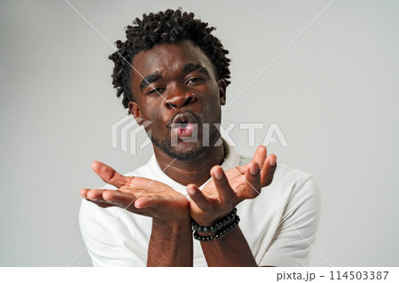 Young African Man Blowing a Kiss Against Gray Background Young African Man Blowing a Kiss Against Gray Background 114503387