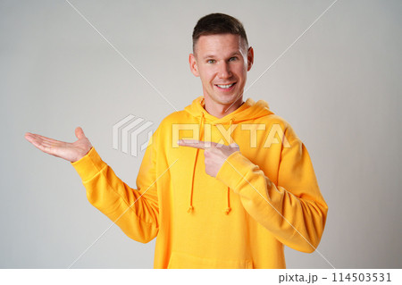 Young man pointing to the side to present a product on gray background Young man pointing to the side to present a product on gray background 114503531