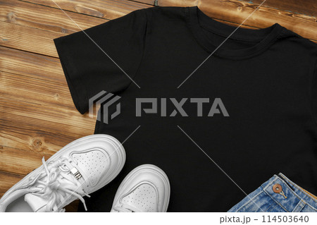 Cotton T-shirt, jeans and sneakers on wooden background top view 114503640