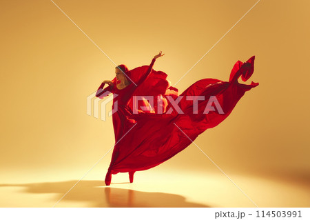 Lyrics of movement, Elegant woman, female dancer in red flowing dress with face covered dancing against sand color background Lyrics of movement, Elegant woman, female dancer in red flowing dress with face covered dancing against sand color background 114503991