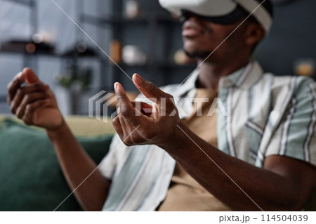 Selective focus shot of unrecognizable African American playing video game in VR headset at home Selective focus shot of unrecognizable African American playing video game in VR headset at home 114504039