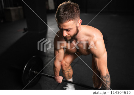 Strong man performing deadlift, lifting barbell from ground. Strength exercise. Routine workout for physical and mental health. Strong man performing deadlift, lifting barbell from ground. Strength exercise. Routine workout for physical and mental health. 114504610
