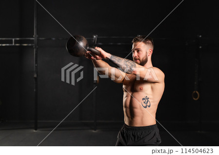 Man performing kettlebell swings, holding kettlebell in both hands. Routine workout for physical and mental health. Man performing kettlebell swings, holding kettlebell in both hands. Routine workout for physical and mental health. 114504623