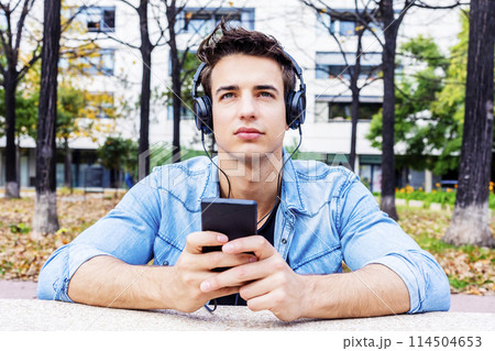 Focused man with headphones in urban park. Focused man with headphones in urban park. 114504653