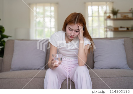 Woman asian frustrated ill sit sofa suffer headache migraine pain have health problem in house living room Woman asian frustrated ill sit sofa suffer headache migraine pain have health problem in house living room 114505156
