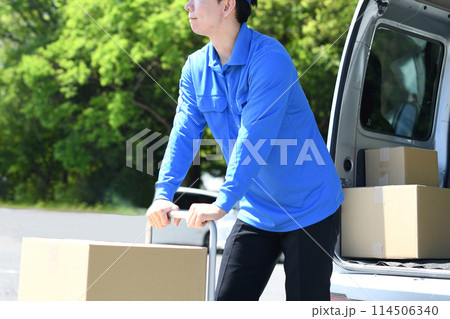 屋外で台車で荷物を運ぶ配送ドライバー 114506340