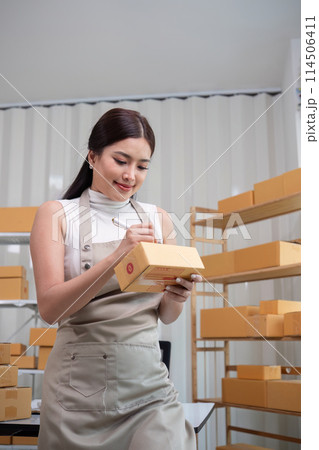 Woman asian in an online store check the customer address and package information on the laptop. Online shopping concept Woman asian in an online store check the customer address and package information on the laptop. Online shopping concept 114506411